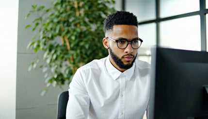 Create an image seeing a person in front of a computer Looking concentrated The background is an office with a plant behind