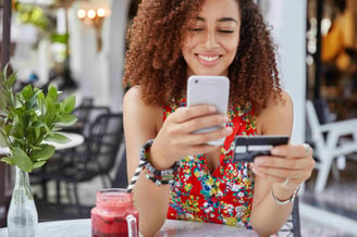 cropped-shot-of-beautiful-african-american-woman-with-happy-look-holds-modern-cell-phone-and-credit-card-makes-shopping-online-jpg